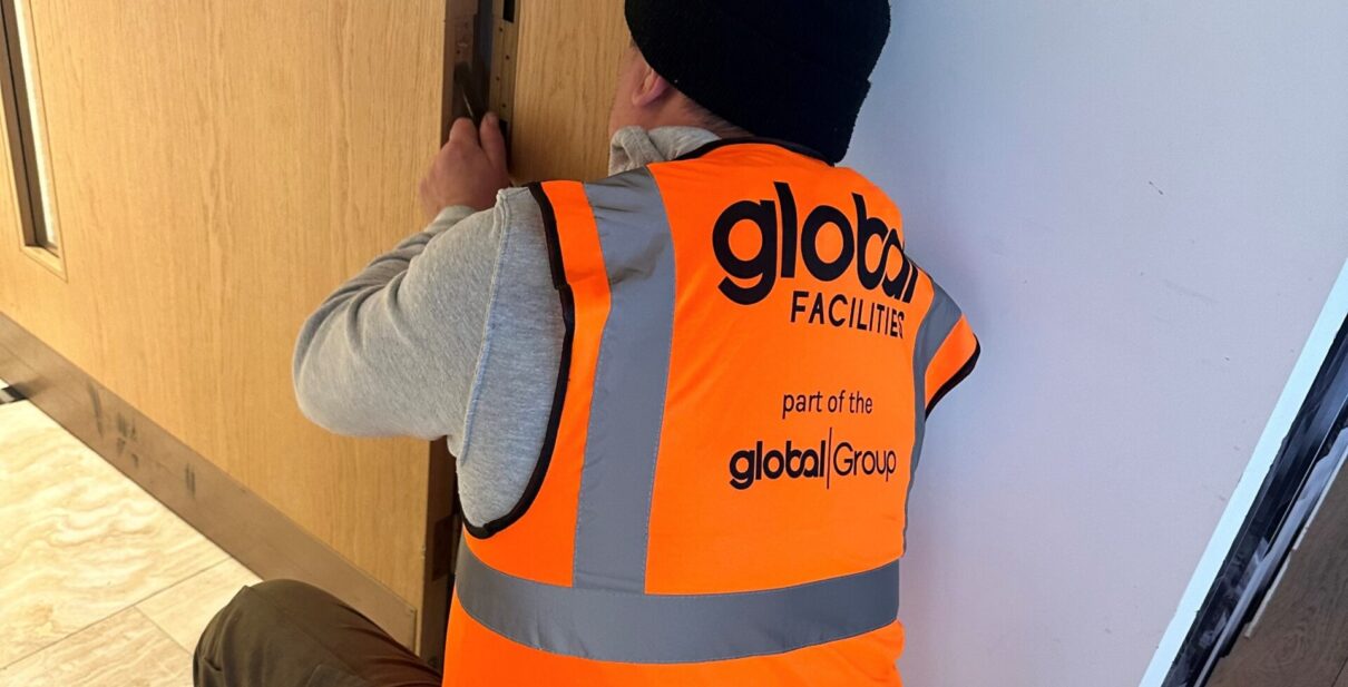 Global Facilities Inspector repairing a fire door