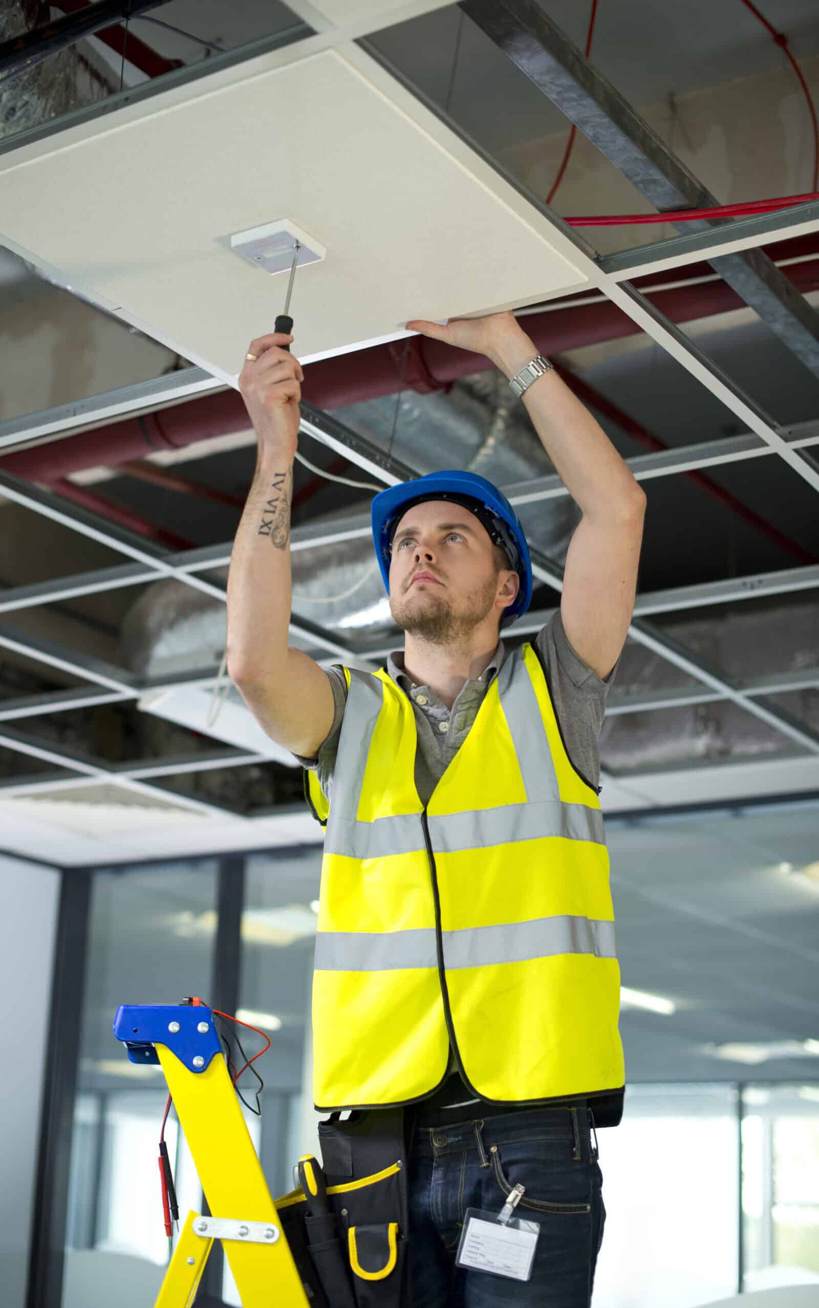 Global Facilities team fitting fire alarm to office interior